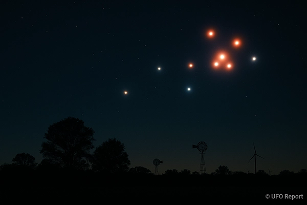 Bright, multi-colored lights moving silently across a dark Texas night sky above silhouetted trees and windmills. Some appear to form a pattern or triangle.